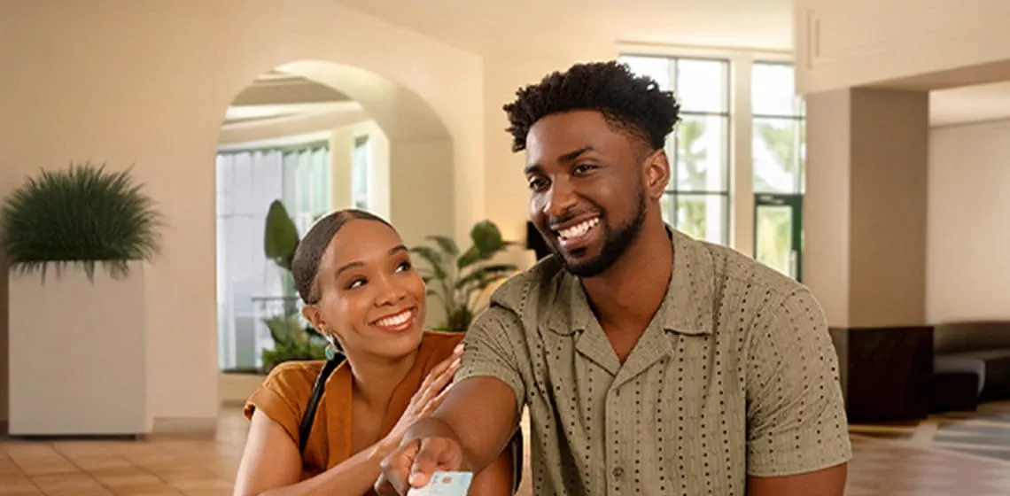 Image of a smiling couple at the reception desk presenting their card